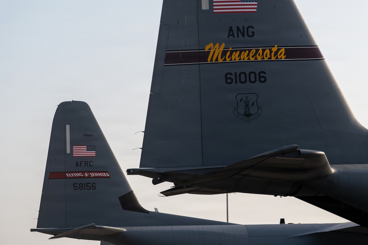 The back of two military aircraft parked side by side.