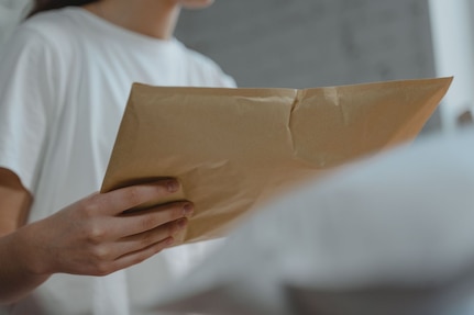 Woman holds yellow envelope package.