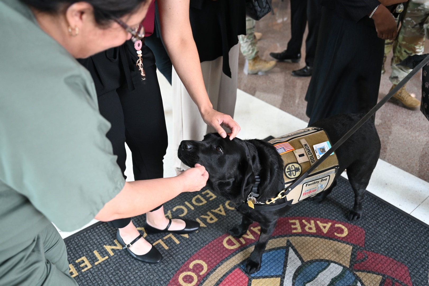 Staff members congratulate and pet CRDAMC facility dog 1st Lt. Solomon following his promotion ceremony June 11 at Fort Hood, Texas. Solomon’s calm presence and ability to connect with people have made him a beloved member of the hospital team and a source of support throughout the organization.