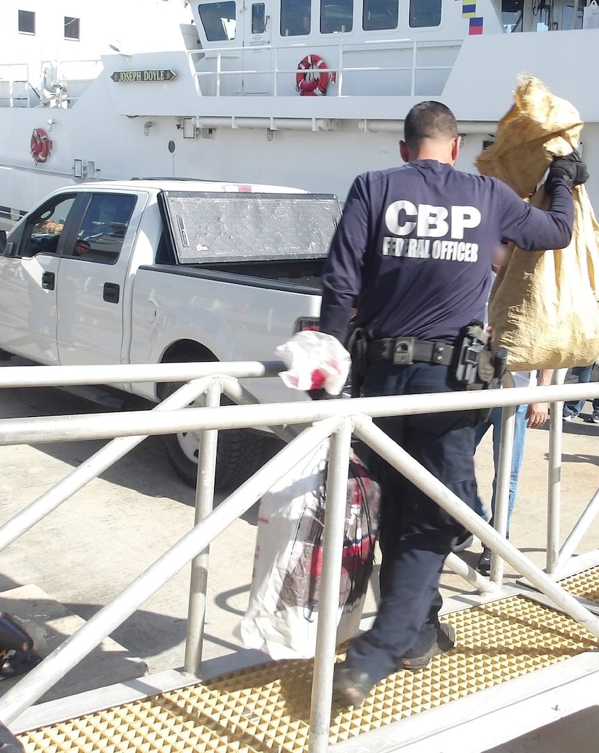 Coast Guard Cutter Isaac Mayo crewmembers and Homeland Security Task Force - San Juan Region law enforcement partners transfer custody of a stowaway and seized a weapon and nine bales of cocaine, with an estimated wholesale value of $4.8 million, at Coast Guard Base San Juan, June 10, 2026. The apprehension and seizure occurred during a Coast Guard boarding of the Crimson Clover Barge off Arecibo, Puerto Rico. This interdiction is part of Homeland Security Task Force – San Juan Region efforts to combat human smuggling, drug trafficking, and deter unlawful maritime migration. (U.S. Coast Guard photo)