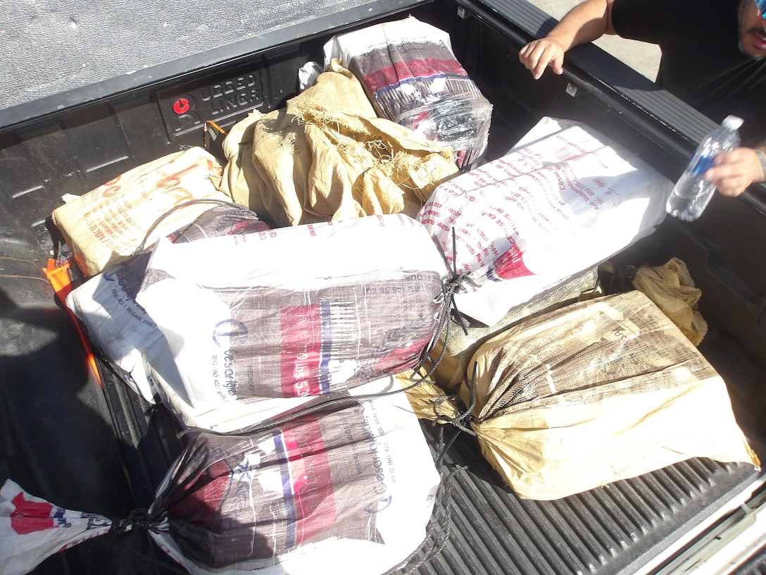 Coast Guard Cutter Isaac Mayo crewmembers and Homeland Security Task Force - San Juan Region law enforcement partners transfer custody of a stowaway and seized a weapon and nine bales of cocaine, with an estimated wholesale value of $4.8 million, at Coast Guard Base San Juan, June 10, 2026. The apprehension and seizure occurred during a Coast Guard boarding of the Crimson Clover Barge off Arecibo, Puerto Rico. This interdiction is part of Homeland Security Task Force – San Juan Region efforts to combat human smuggling, drug trafficking, and deter unlawful maritime migration. (U.S. Coast Guard photo)