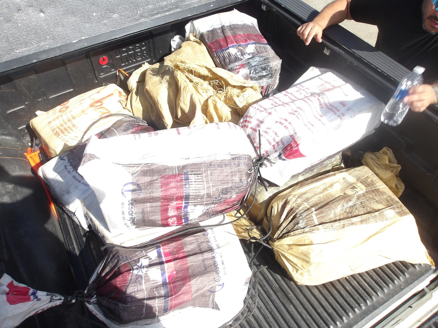 Coast Guard Cutter Isaac Mayo crewmembers and Homeland Security Task Force - San Juan Region law enforcement partners transfer custody of a stowaway and seized a weapon and nine bales of cocaine, with an estimated wholesale value of $4.8 million, at Coast Guard Base San Juan, June 10, 2026. The apprehension and seizure occurred during a Coast Guard boarding of the Crimson Clover Barge off Arecibo, Puerto Rico. This interdiction is part of Homeland Security Task Force – San Juan Region efforts to combat human smuggling, drug trafficking, and deter unlawful maritime migration. (U.S. Coast Guard photo)