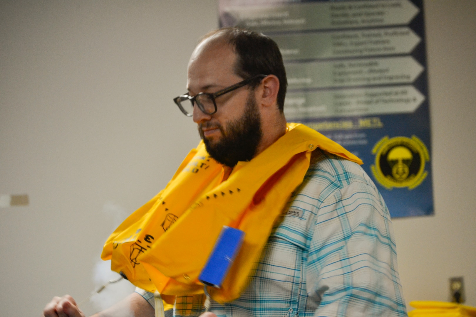 A Defense Logistics Agency Troop Support employee pulls the inflation cord on an aviation life preserver unit during an aircrew flight equipment demonstration with the 108th Wing. The hands-on exercise was part of the biannual Troop Support Academy, which connects civilian procurement specialists with the physical, life-saving gear they source for the warfighter.