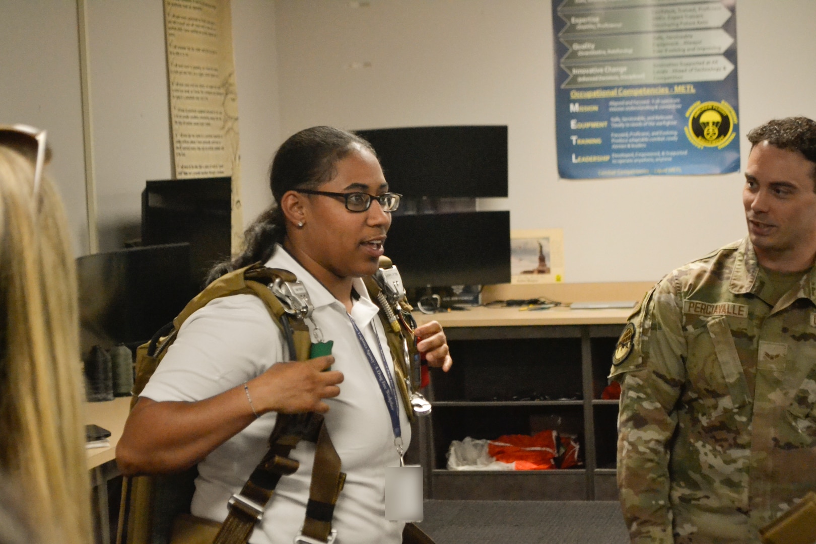 A Defense Logistics Agency Troop Support Academy participant adjusts the straps of an emergency passenger parachute harness during a hands-on equipment brief. The demonstration provided DLA’s civilian workforce with a boots-on-the-ground perspective of the safety and survival systems relied upon by military aircrews daily.
