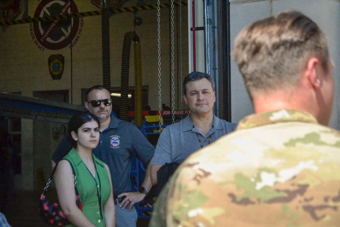 Defense Logistics Agency Troop Support Academy participants listen to an operational briefing inside a Joint Base McGuire-Dix-Lakehurst fire station. The briefing highlighted how DLA's Construction and Equipment supply chain provides essential support, vehicle parts, and safety gear to military emergency services.