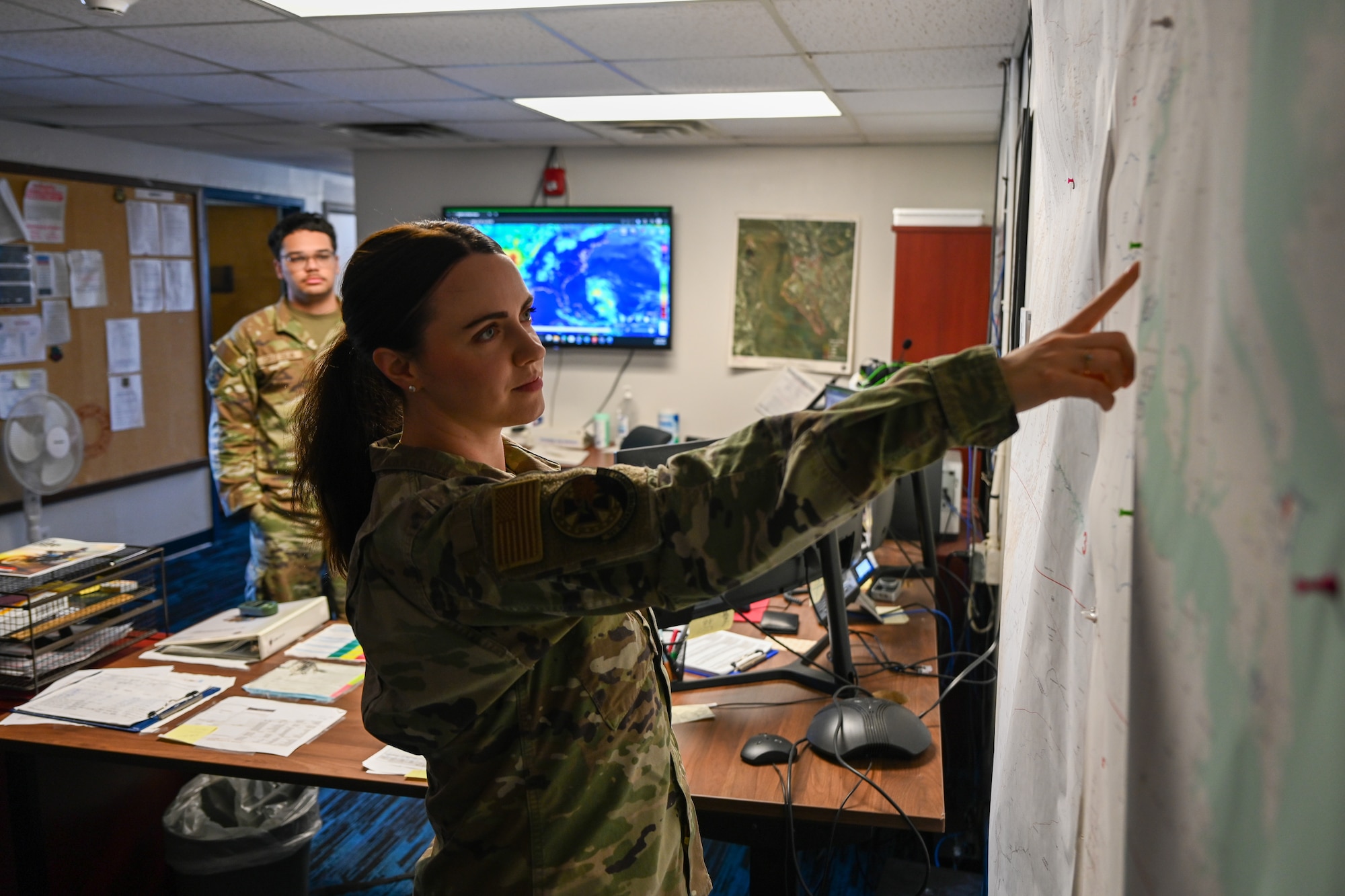 Airman points at a map on the wall. (U.S. Air Force photo by Airman 1st Class Donnell Ramsey)