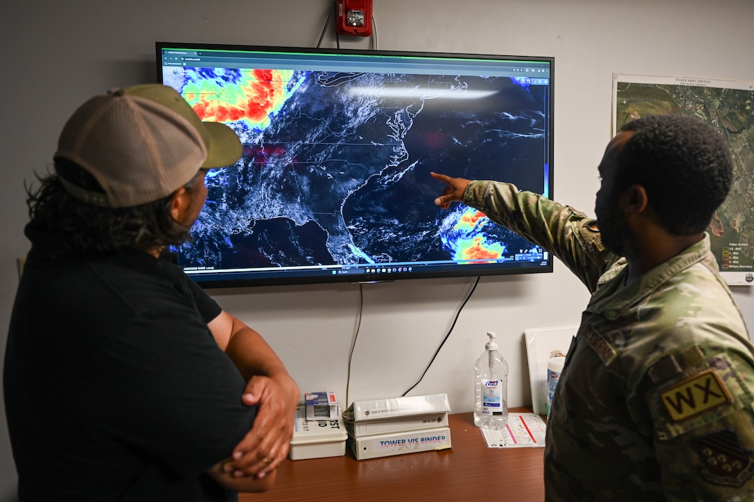 Airman points at tv next to civilian. (U.S. Air Force photo by Airman 1st Class Donnell Ramsey)
