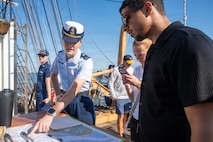 A photo of two people conversing aboard the U.S. Coast Guard Cutter Eagle.