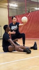 Linda Pai, head coach for Team Army sitting volleyball, demonstrates proper serving technique to U.S. Army Cpl. Dela Bush during sitting volleyball practice at Army Team Sports Camp in San Antonio, May 2026.