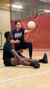 Linda Pai, head coach for Team Army sitting volleyball, demonstrates proper serving technique to U.S. Army Cpl. Dela Bush during sitting volleyball practice at Army Team Sports Camp in San Antonio, May 2026.