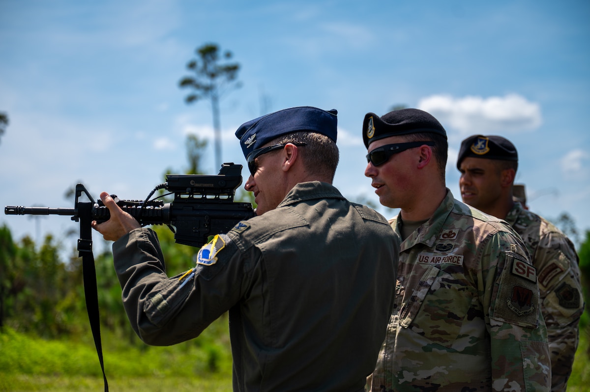 U.S. Air Force Col. Christian Bergtholdt, 325th Fighter Wing commander, aims an M4 carbine equipped with a SMASH 2000 fire control system while Master Sgt. Jonathan Calo, 325th Security Forces Squadron logistics and readiness superintendent, and Senior Master Sgt. Reginald Walters, 325th SFS future operations superintendent, observe at Tyndall Air Force Base, Florida, June 3, 2026. Base leaders conducted a live-fire demonstration of a future training plan designed to qualify defenders on specialized weapon systems to neutralize small unmanned aircraft systems. (U.S. Air Force photo by Airman 1st Class Rosario Garcia)