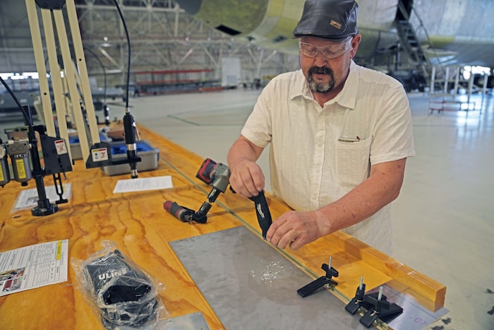 Photo shows man sweeping together clipping on stop of a metal sheet