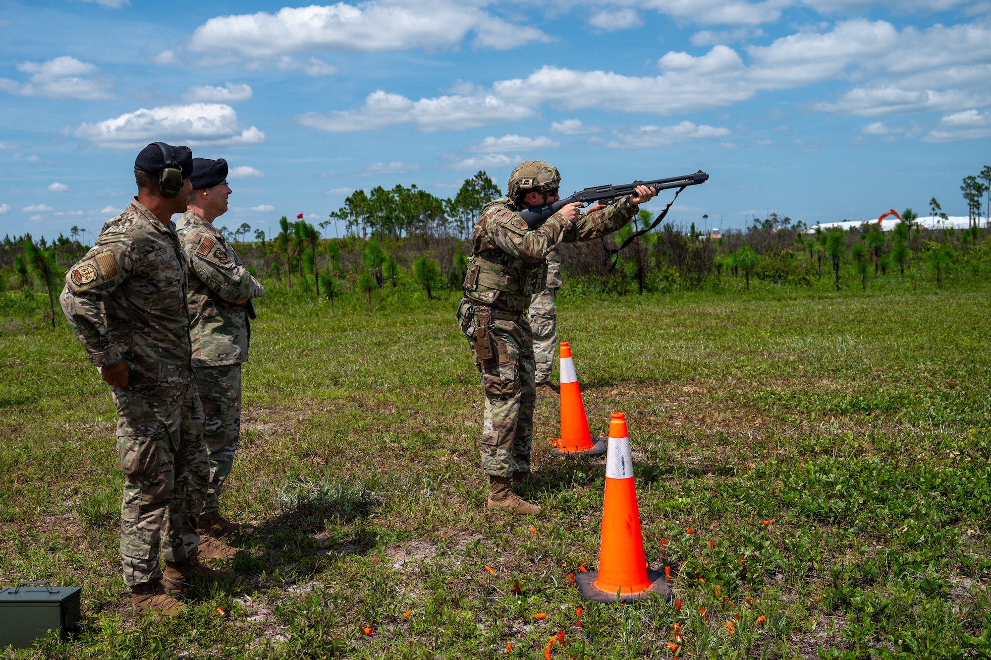 U.S. Air Force Tech. Sgt. Nicholas Rhoades, 325th Security Forces Squadron training and standardization section chief, right, aims an M870 shotgun as Maj. Gen. Thomas P. Sherman, Air Force Installation and Mission Support Center commander, and Senior Master Sgt. Reginald Walters, 325th SFS future operations superintendent, observe at Tyndall Air Force Base, Florida, June 3, 2026. During the demonstration, Rhoades engaged simulated aerial targets to highlight the squadron's evolving capability to neutralize low-altitude, high-speed airborne threats. (U.S. Air Force photo by Airman 1st Class Rosario Garcia)