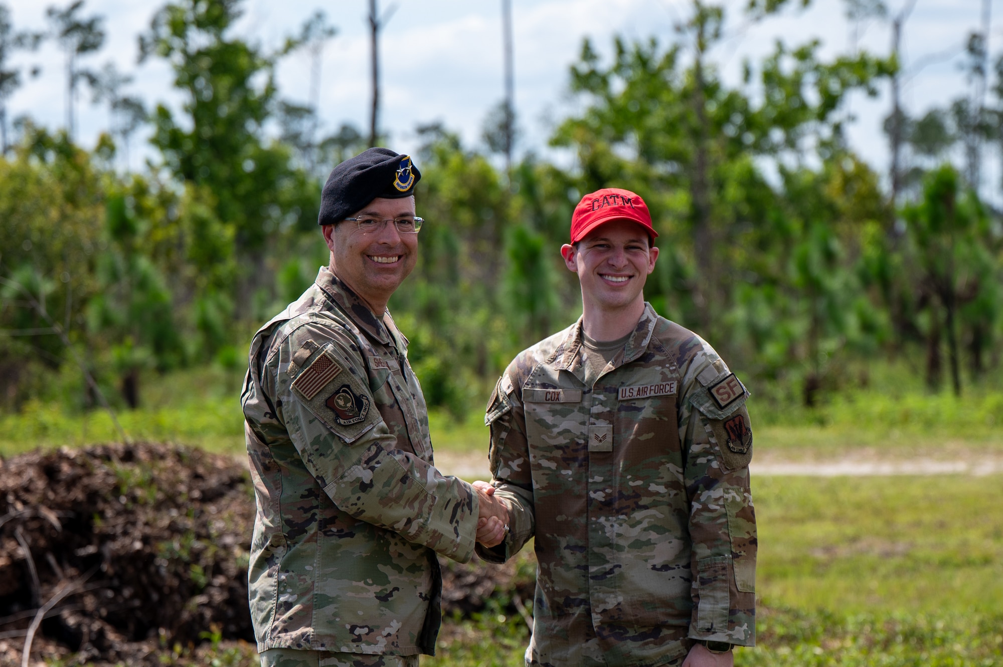 U.S. Air Force Maj. Gen. Thomas P. Sherman, Air Force Installation and Mission Support Center commander, coins Senior Airman Matthew Cox, 325th Security Forces Squadron combat arms training and maintenance instructor, during a visit to Tyndall Air Force Base, Florida, June 3, 2026. Sherman recognized Cox for his outstanding performance and direct contributions as a lead instructor for the squadron's new counter-small unmanned aircraft systems training. (U.S. Air Force photo by Airman 1st Class Rosario Garcia)