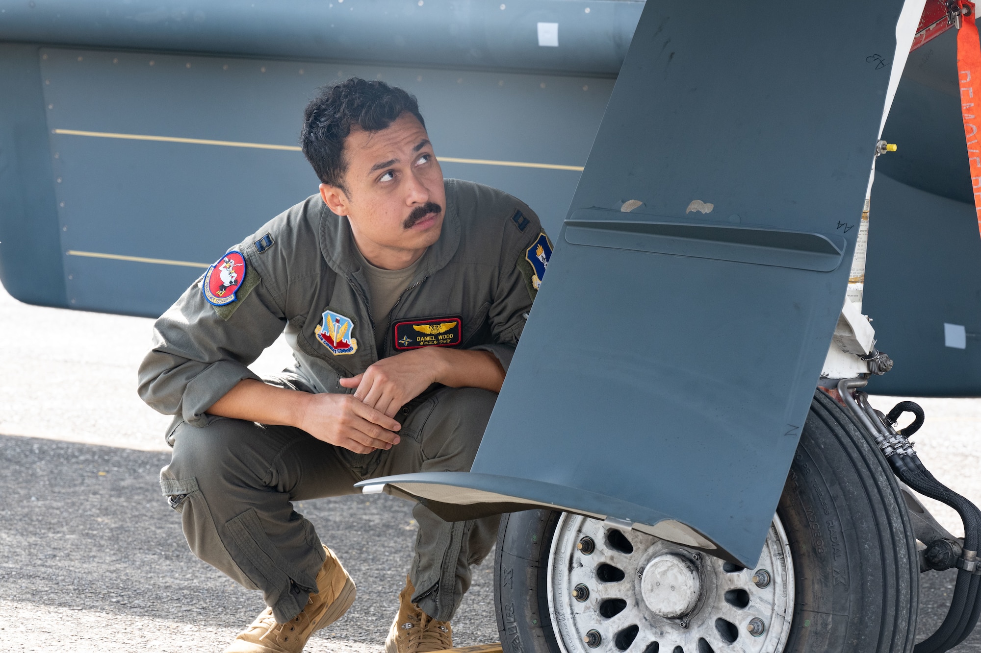 A servicemember crouches under an aircraft