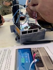An end user loads a flow cell on a modified field sequencing device during Beholder’s Gaze training, Oct. 24, 2024. The event was attended by the U.S. Naval Research Laboratory and U.S. Army Combat Capabilities Development Command (DEVCOM) Chemical Biological Center military operators Far-Forward Advanced Sequencing Technology (F-FAST) team who conducted training and provided the technology/system. The effort brings sophisticated laboratory capability into austere environments, giving forward-deployed units the ability to detect and identify harmful pathogens in less than 30 minutes. Unlike conventional sequencing systems, Far-Forward Biological Sequencing (FFBS) is tailored for military personnel who may not have formal laboratory training. (U.S. Navy photo)