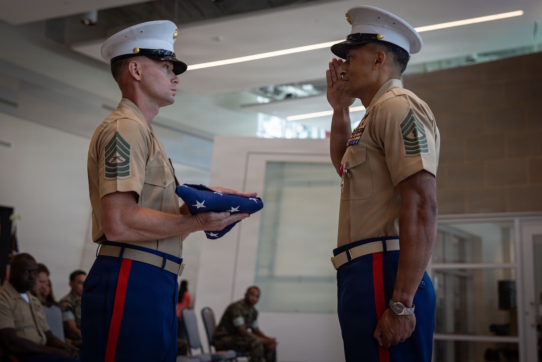 U.S. Marine Corps Master Sgt. Cody Smith, left, operations chief, 2nd Marine Logistics Group, presents a folded flag to Master Gunnery Sgt. Steven Upsher, communications chief, 2nd MLG, during an Old Glory presentation as part of a retirement ceremony in Jacksonville, North Carolina, June 9, 2026. Upsher retired after 30 years of dedicated and faithful service to the U.S. Marine Corps. Smith is a native of Florida. Upsher is a native of Minnesota. (U.S. Marine Corps photo by Staff Sgt. Makayla Elizalde)