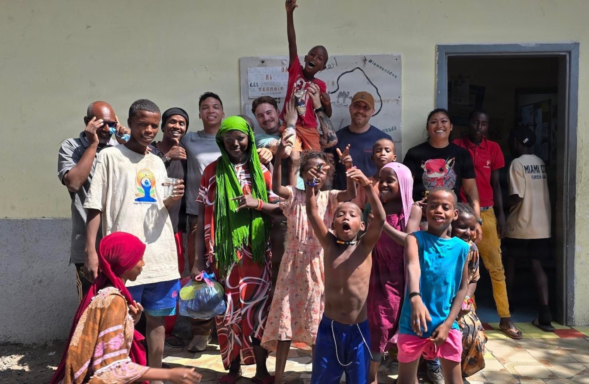 Air National Guardsmen take a photo with locals while volunteering at a orphanage during their deployment in Djibouti, Feb. 21. Members of the 130th Airlift Wing set up a medical clinic to assist with wound care for the local populace.