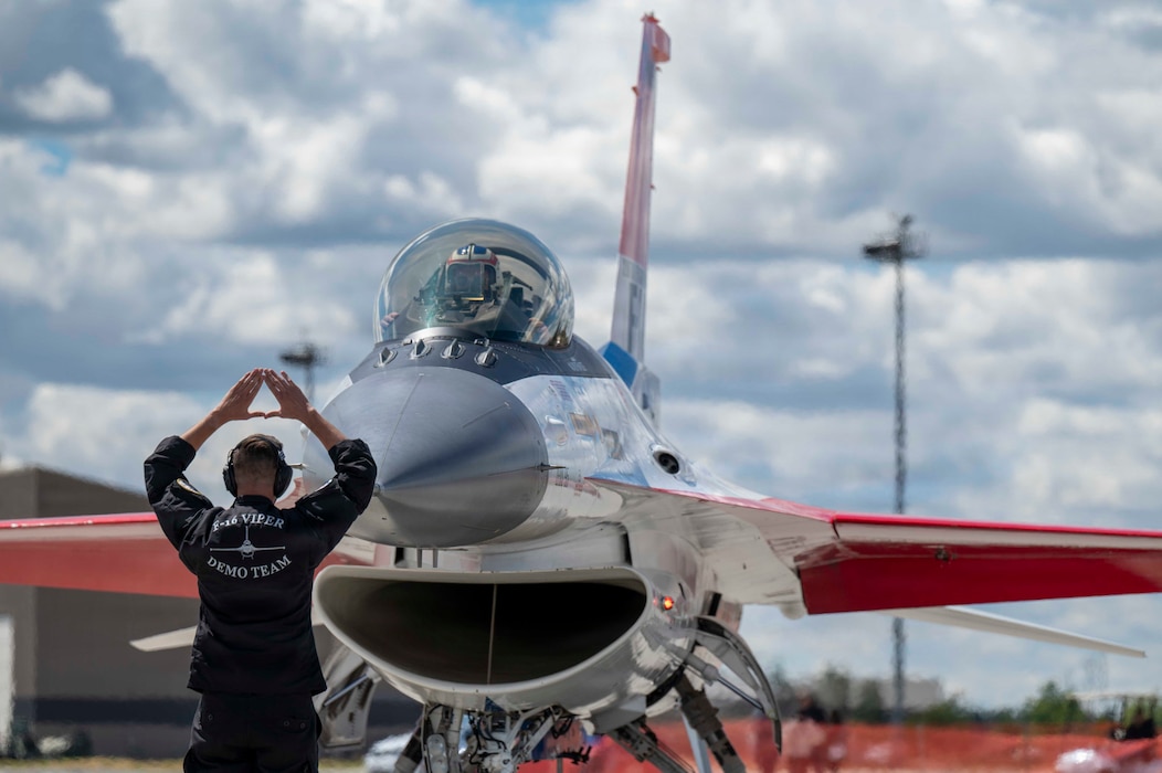 A member of the F-16 Viper Demonstration Team marshals a commander and pilot, into its parking position.