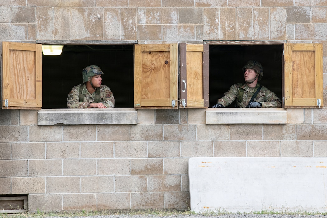 Two airmen in a building looking at eachother through window as they check out the field.