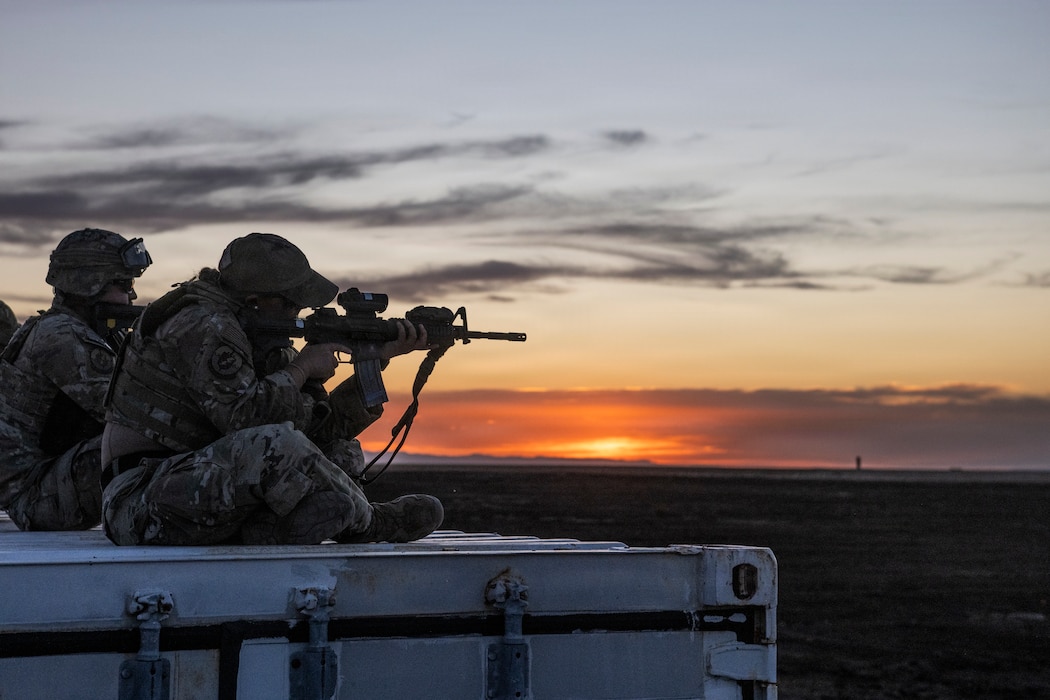 Airmen assigned to the 124th Fighter Wing's Security Forces Squadron participate in a field training exercise, pointing their weapon at target at sunset.