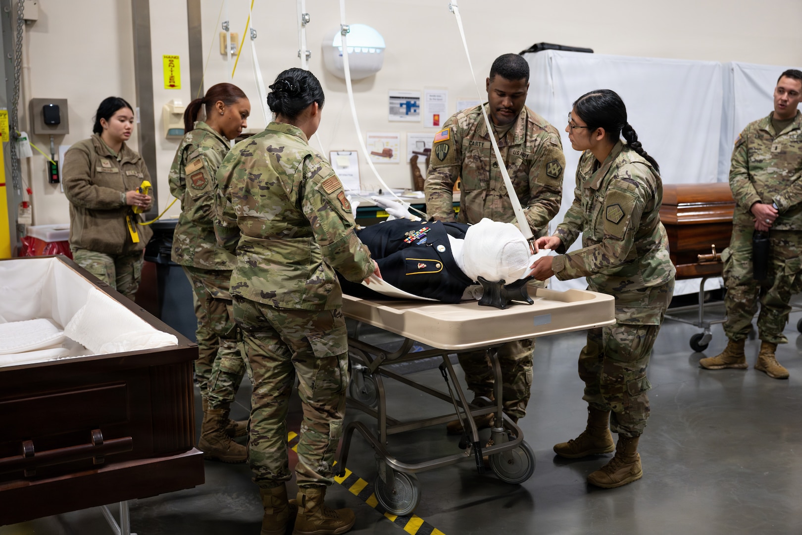Soldiers practice moving remains into a casket with the use of a mannequin