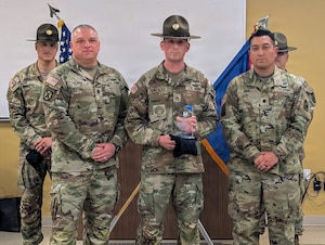 Three soldiers stand beside each other.