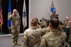 A uniformed service member salutes a formation.