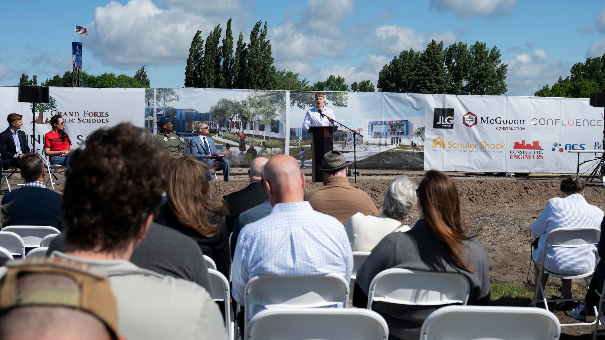 A man speaks to a crowd on a construction site.