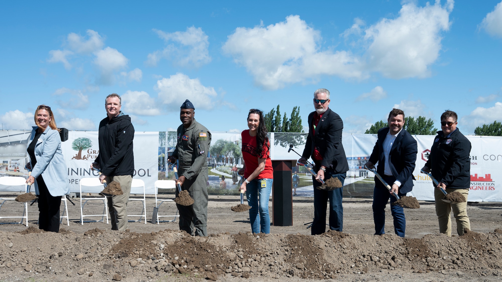 Seven people shovel dirt on a construction site.