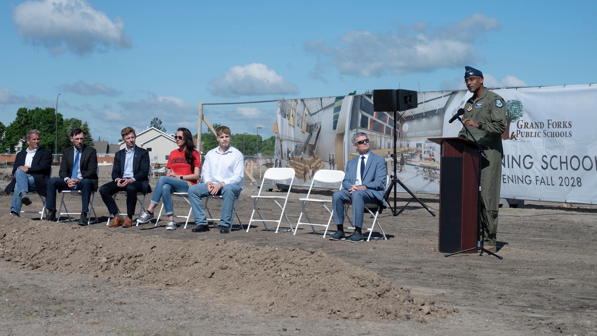 A man speaks to a crowd at a construction site.