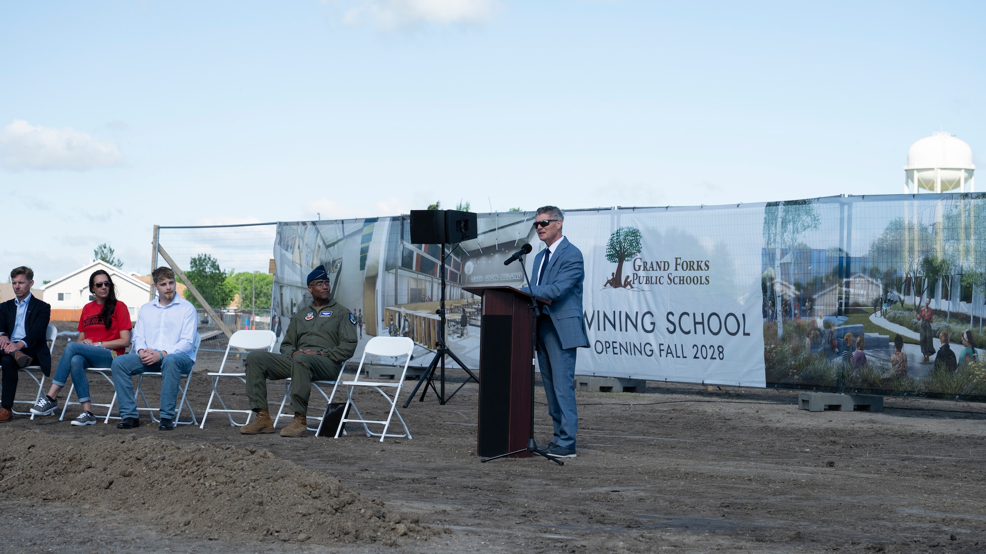 A man speaks to a crowd on a construction site.