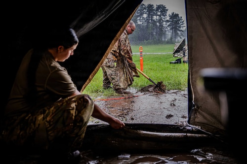 Woman removes water from tent.