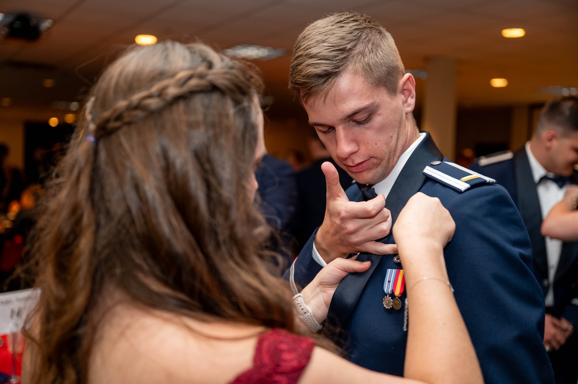 A pilot receives his silver wings with assistance from his guest.