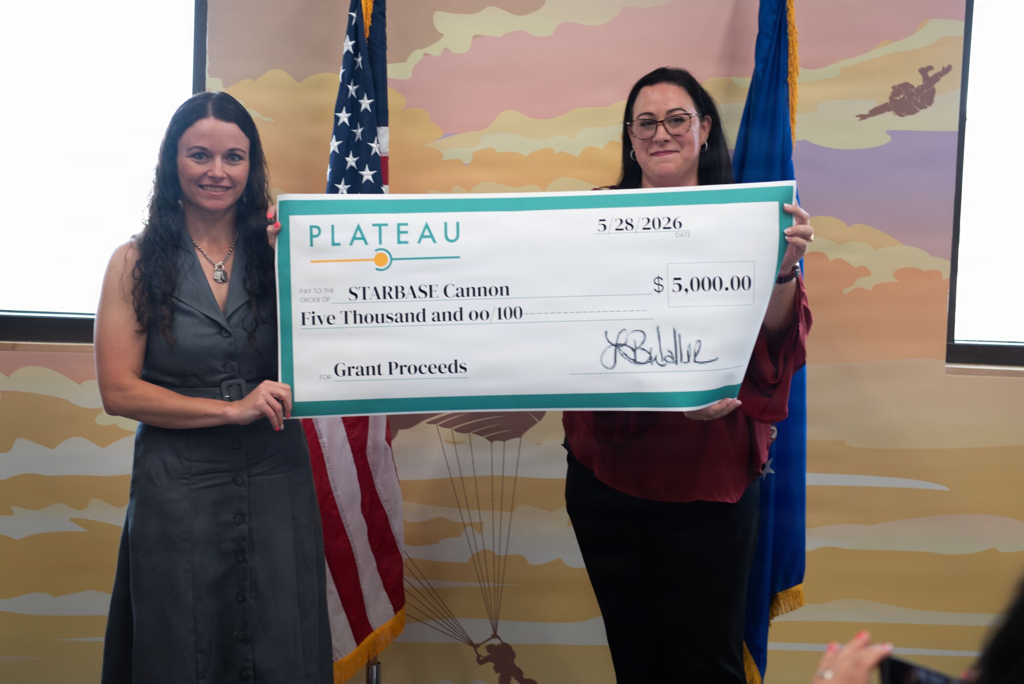 Two women hold up a large paper check.