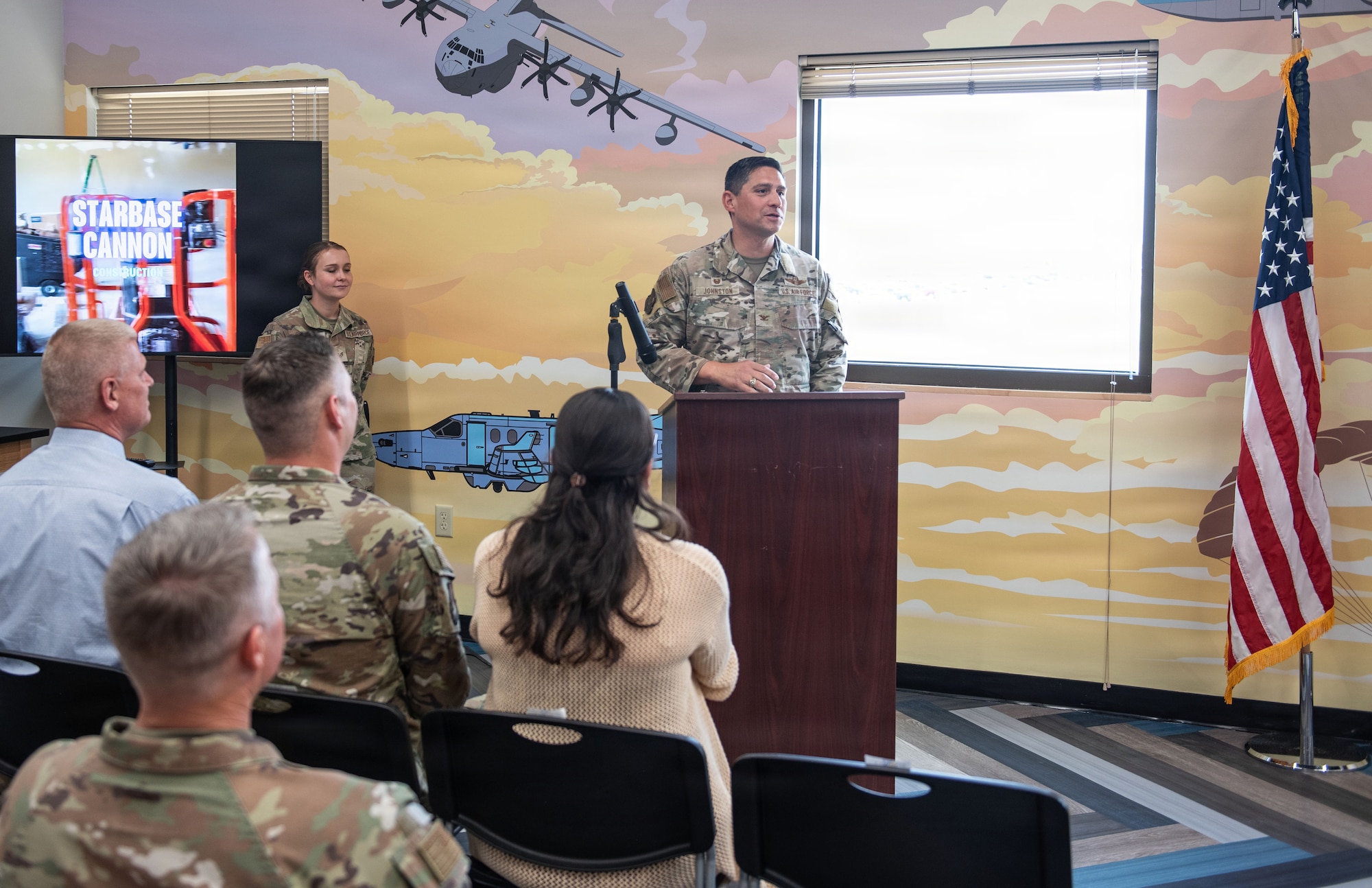 A man in a camouflage uniform address a crowd.
