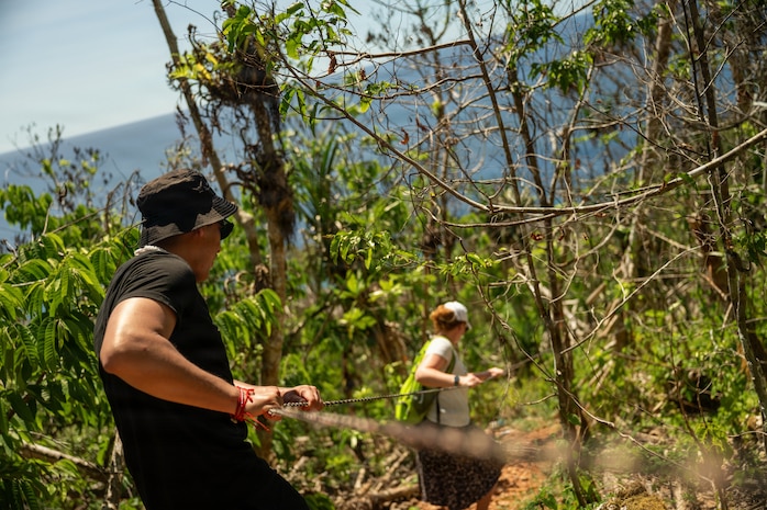 U.S. Air Force Senior Airman Luis Huallpa Jurado, 439th Communications Squadron radio frequency technician and Staff Sgt. Ashley Bowman, 439th Aeromedical Evacuation Squadron expeditionary communications technician, holds onto a guide line while navigating steep terrain during Cyber Guam 2026 near Dededo, Guam, June 8th, 2026.