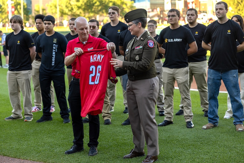 Matt Guay, Indianapolis Indians vice president and general manager, presents an Indians jersey to Brig. Gen. Sara Dudley, U.S. Army Recruiting Division commanding general, in front of 16 Future Soldiers before an Indians baseball game at Victory Field in Indianapolis June 12, 2026. The Indians paid special tribute to the 251st birthdays of both the U.S. Army and Army Finance Corps. (U.S. Army photo by Mark R. W. Orders-Woempner)