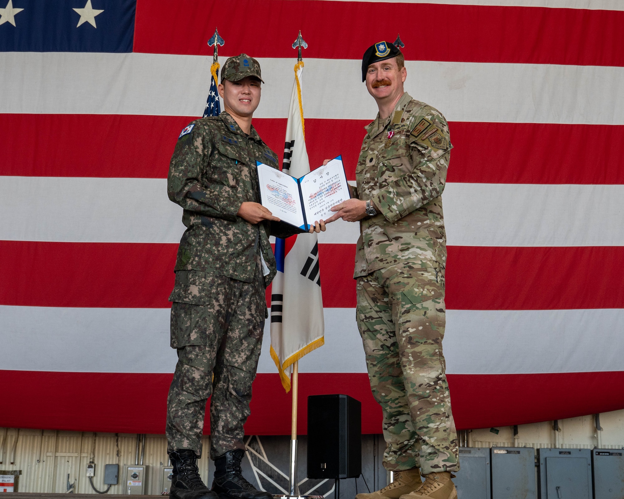 Republic of Korea Air Force Maj. Jay Wook Chang, 38th Military Police Unit commander, presents U.S. Air Force Lt. Col. Ryan Kiggings, 8th Security Forces Squadron outgoing commander, with the ROKAF certificate of appreciation during the 8th SFS change of command ceremony at Kunsan Air Base, Republic of Korea, June 12, 2026. Change of command ceremonies preserve military traditions and formally transfer leadership of a unit. (U.S. Air Force photo by Staff Sgt. Cedrique Oldaker)