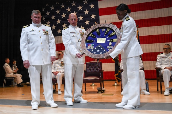 Navy Capt. Chad Roe, left, is presented with a ship's wheel shadow box - depicting his ranks, awards and 12 duty stations over his 30-year Navy career in the Medical Service Corps. He retired after he relinquished command of NMRTC Great Lakes at the Capt. James A. Lovell Federal Health Care Center in North Chicago, Ill.