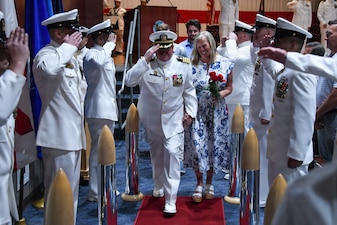 Navy Capt. Chad Roe escorts his wife, Pam Roe, "ashore" after his retirement ceremony at the Capt. James A. Lovell Federal Health Care Center in North Chicago, Ill. Roe's retirement ceremony followed his change of command, where he turned over command of NMRTC Great Lakes to Capt. Afshin Afarin.