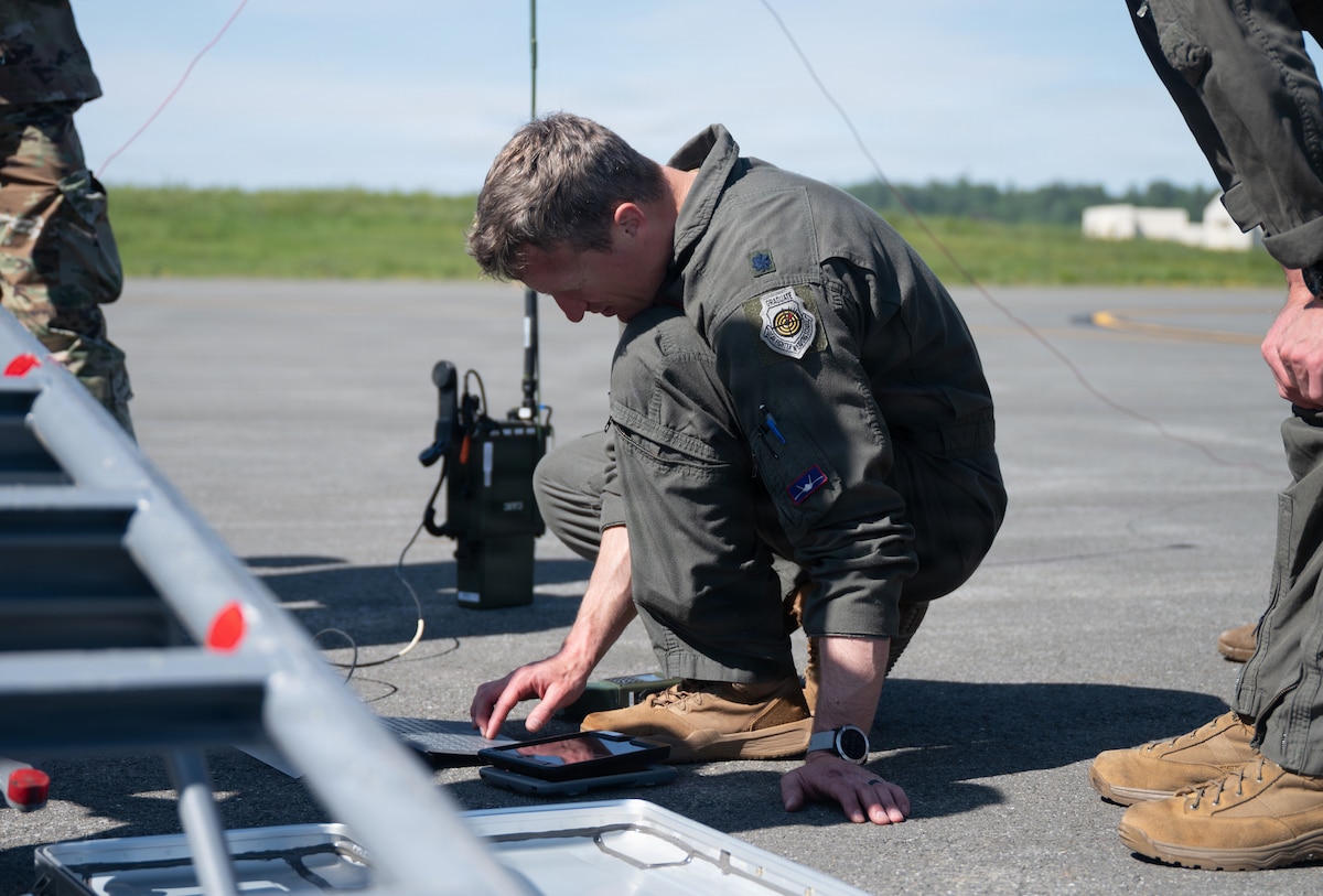 Pilot kneels in front of computer screen.