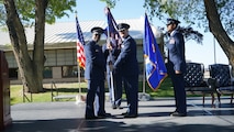 photo of USAF Airmen standing on a stage, two Airmen are holding a unit flag in between them