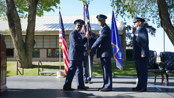 photo of USAF Airmen standing on a stage, two Airmen are holding a unit flag in between them