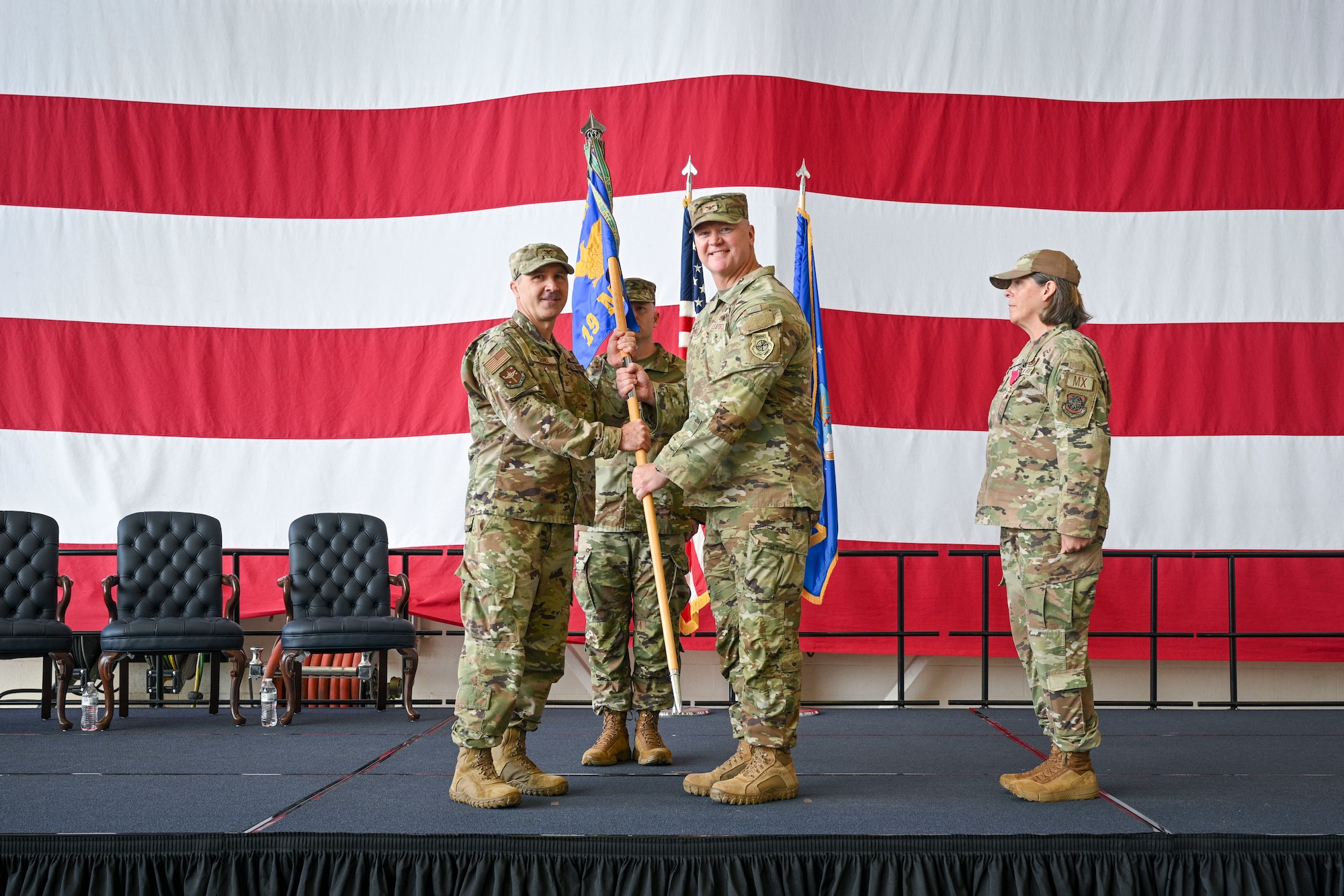U.S. Air Force Col. Bret Echard passes a guidon to Col. Kevin Scholz during a change of command ceremony.