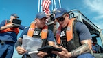 Petty Officer 2nd Class Fabian Monarrez and Petty Officer 2nd Class Merrit Carter use TRITON to conduct a boarding inspection during a live demonstration in Washington on May 19, 2026.  Developed by MLE and CG-RAPTOR, TRITON is a voice-activated iPad application that speeds the boarding process. If testing goes well, could be rolled out to the fleet in fall.