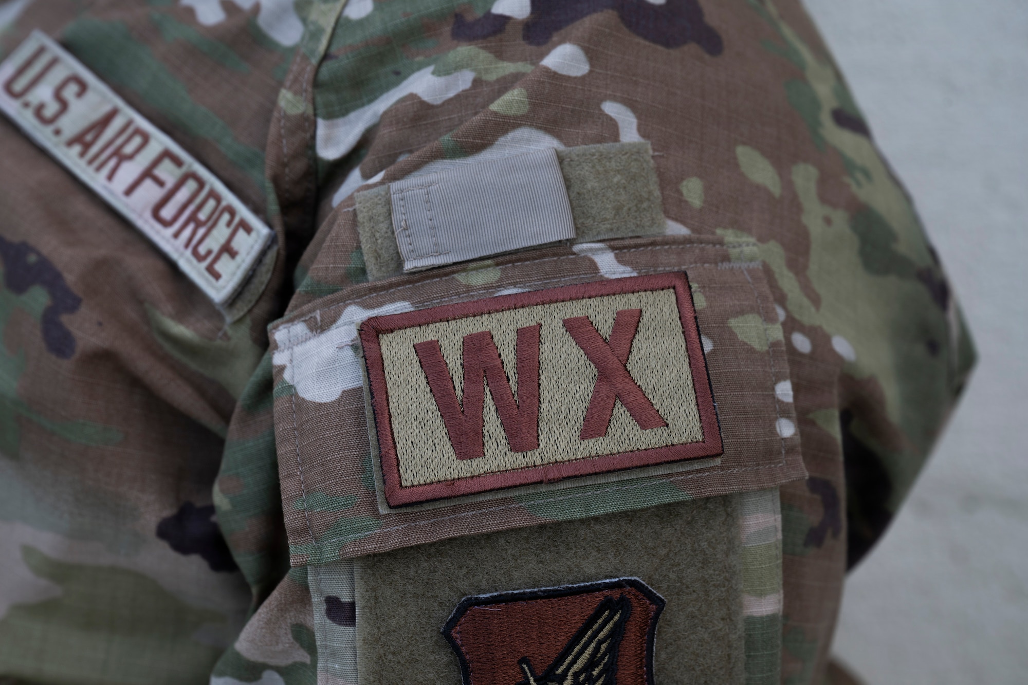 A patch of the letters "WX" denoting the weather Air Force specialty code appears on an Airman's uniform