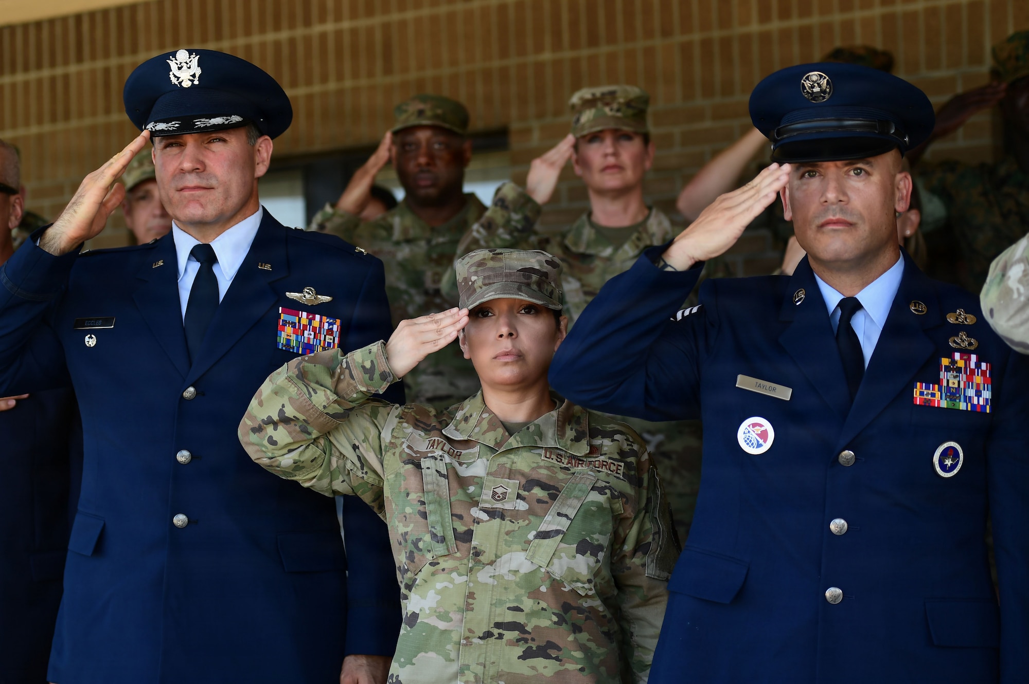 Men and women in military uniform render a salute.