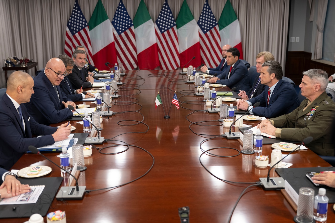 U.S. and Italian leaders sit and table at a conference table.