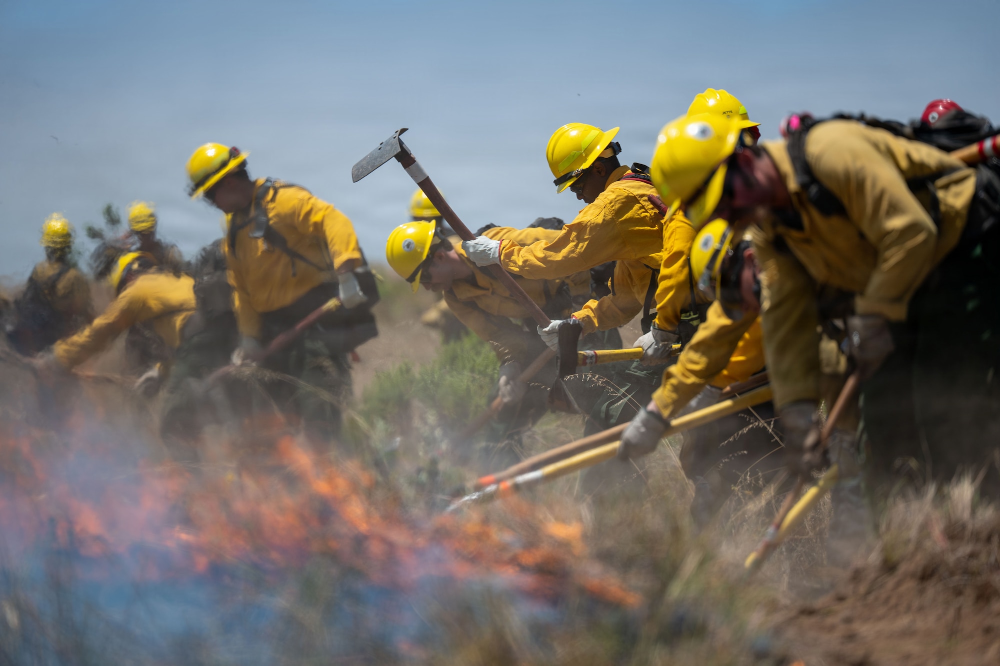 A group of people dig into the ground around an active fire